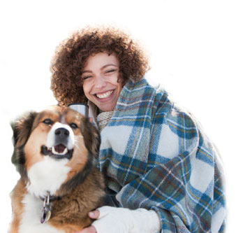 Woman in the mountains with snow, a blanket and a dog.